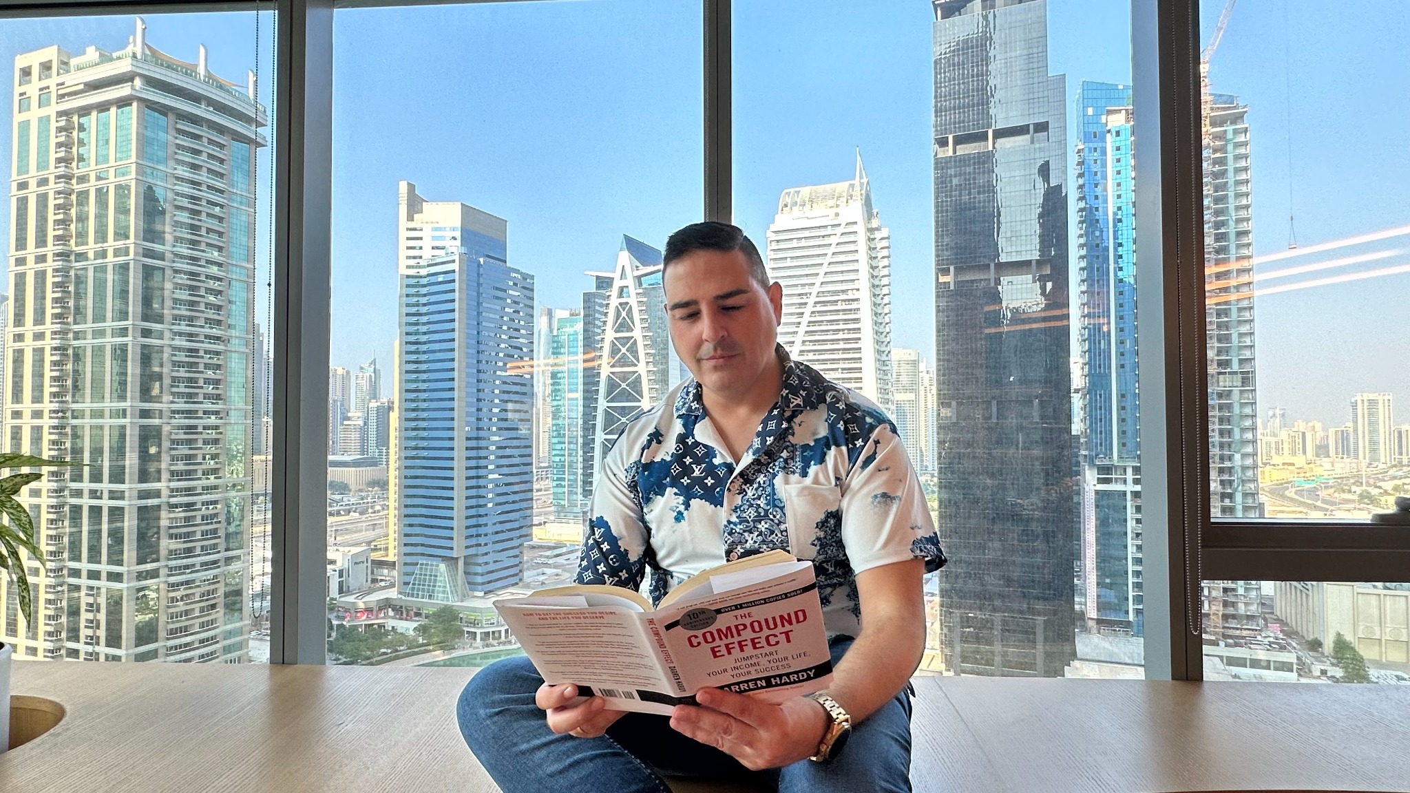 Francisco Bañón leyendo junto a una ventana con vistas urbanas