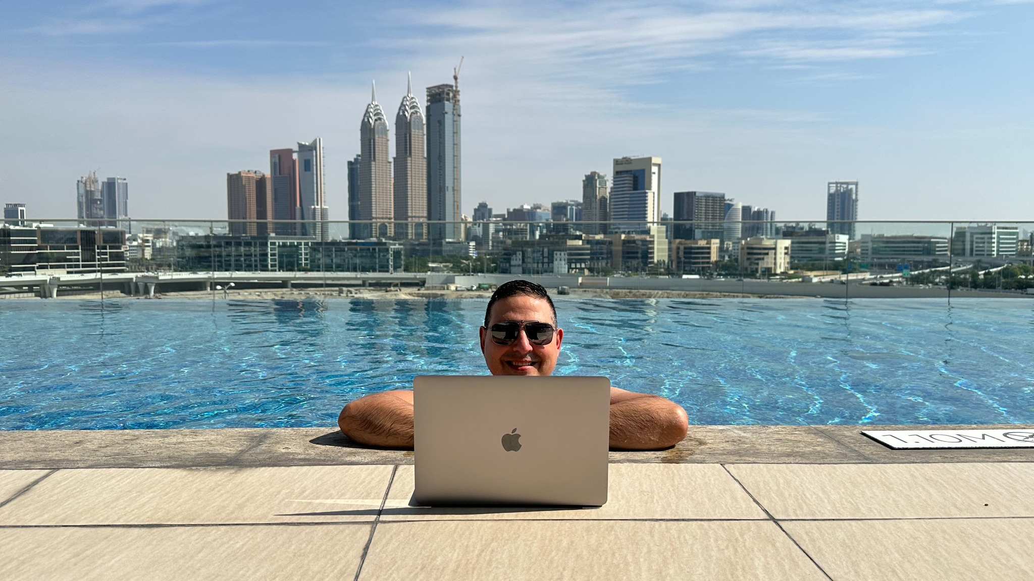 Francisco Bañón trabajando con un portátil junto a una piscina con el skyline de Dubái