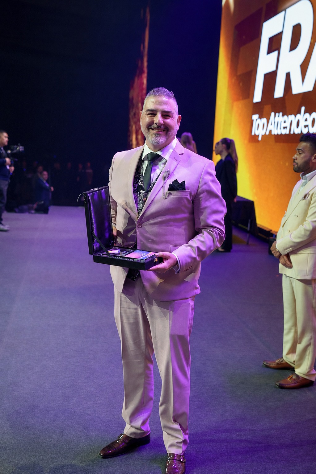 Francisco Bañón sosteniendo un reconocimiento en un evento profesional